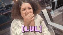 a woman with curly hair is laughing with the words [ lul ] behind her