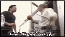 two men are standing next to each other and one of them is holding a knife in his hand .
