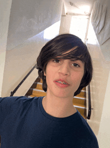 a young boy with braces on his teeth stands in front of some stairs