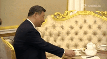 a man in a suit sits at a table with a kremlin.ru logo in the corner