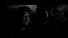 a man with a beard is talking to another man in a dark room and saying `` let 's call it war '' .