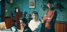 three young men are standing in a room with their arms crossed