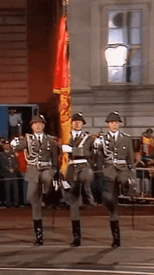 a group of soldiers marching in a parade holding a flag