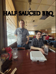 two men sitting at a table in a diner with half sauced bbq written on the top