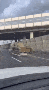 a military vehicle is driving down a highway on a trailer .