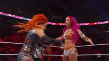 two women are wrestling in a ring with a sign that says ' w ' on it