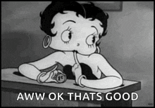 betty boop is sitting at a desk with a pencil in her mouth and says `` aww ok thats good '' .