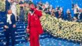 a man in a red suit is standing on a staircase in front of a crowd of people .