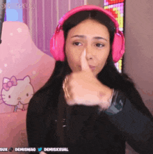 a woman wearing pink headphones is giving a thumbs up sign .