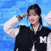 a woman wearing a black and white jacket with the letter m on it salutes