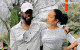 a man and a woman are standing next to each other in a park . the woman is wearing a white shirt .