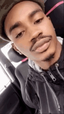 a man with a beard is taking a selfie in a car .
