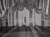 a black and white photo of a stage with white curtains hanging