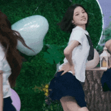 a girl in a white shirt and blue skirt is dancing in front of a green wall .