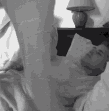 a man is laying on a bed with his legs up and a lamp in the background .
