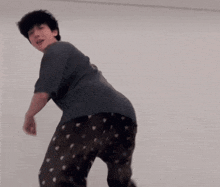 a man in pajamas is dancing in a room with a white wall .