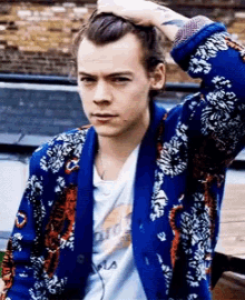 harry styles is wearing a blue jacket with a floral pattern and a white shirt .