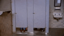 a man is standing in a public restroom behind a stall .