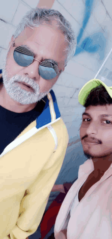 a man with a beard wearing sunglasses and a yellow jacket poses with another man