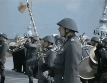 a man in a helmet stands in front of a band playing brass instruments