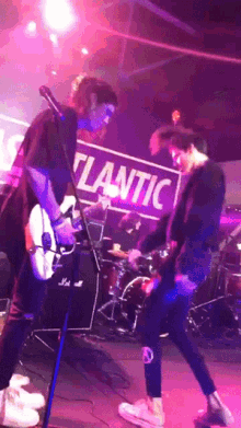 a man playing a guitar on stage in front of a sign that says " atlantic "