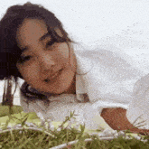 a woman in a white shirt is smiling while laying in the grass