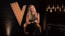 a woman in a black dress is making a funny face in front of a bunch of lights .