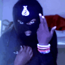 a person wearing a ski mask with a money bag on it giving the middle finger .