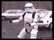 a storm trooper is dancing in a parking lot in front of a wall .