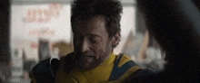 a man in a yellow and blue jacket is talking to a woman in a restaurant .