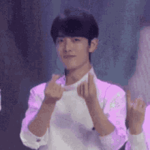 a man in a white shirt is making a heart with his hands .