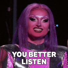 a drag queen with purple hair and red face says you better listen