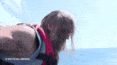 a man wearing a life jacket is swimming in the ocean