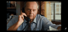 a man in a striped shirt and tie talks on a phone