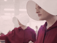 a woman in a white hat is standing next to another woman in a red hoodie .