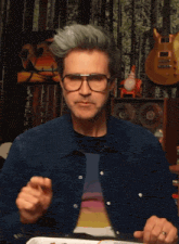 a man wearing glasses and a rainbow shirt is eating