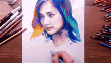 a drawing of a woman with blue hair is on a table next to colored pencils