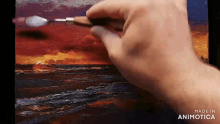 a person is painting a sunset over the ocean with a spatula .