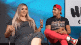 a pregnant woman sits next to a man who is wearing a shirt that says eazy eazy eazy