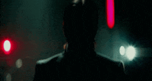 a close up of a man 's face in a dark room with a red light behind him .