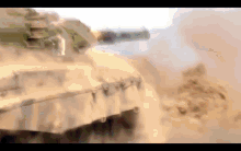 a military tank is driving through a sandy area