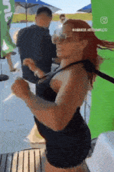 a woman in a black dress is dancing in front of a green banner that says amanda