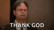 a man in a suit and tie is raising his arms in the air with the words `` thank god '' behind him .