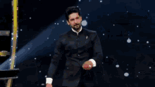 a man in a suit is dancing on a stage in front of a mirror .