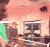 a person in a green shirt is standing in a room with a rope around their neck .