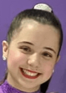 a close up of a young girl 's face with a purple background .