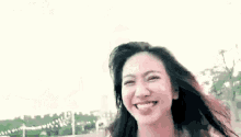 a young woman in a white dress is standing in a park holding her hair .