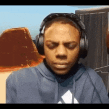 a man wearing headphones and a blue hoodie is looking down .