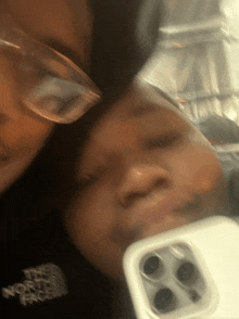 a person wearing glasses and a north face shirt is taking a selfie