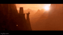 a couple of people standing on top of a bridge in the middle of a valley .